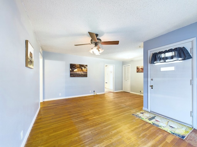 foyer with ceiling fan, a textured ceiling, and hardwood / wood-style floors