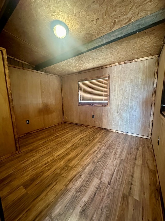 additional living space featuring wood-type flooring and wooden walls