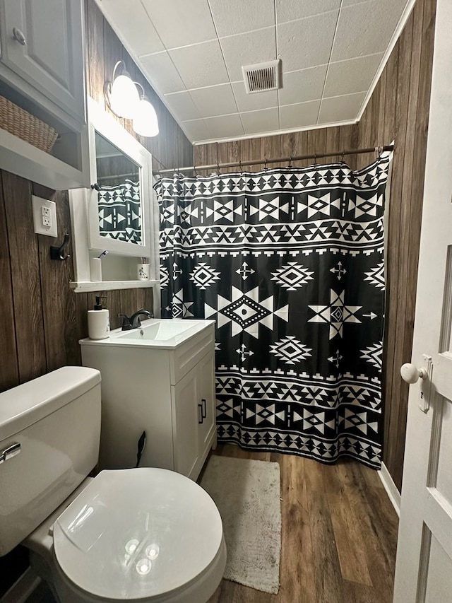 bathroom with hardwood / wood-style flooring, vanity, toilet, and wooden walls