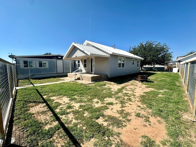 back of property with a fire pit and a lawn