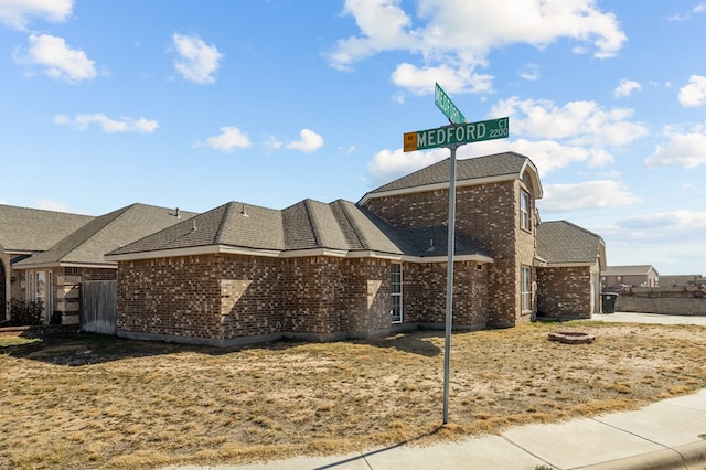 view of home's exterior featuring roof with shingles and brick siding