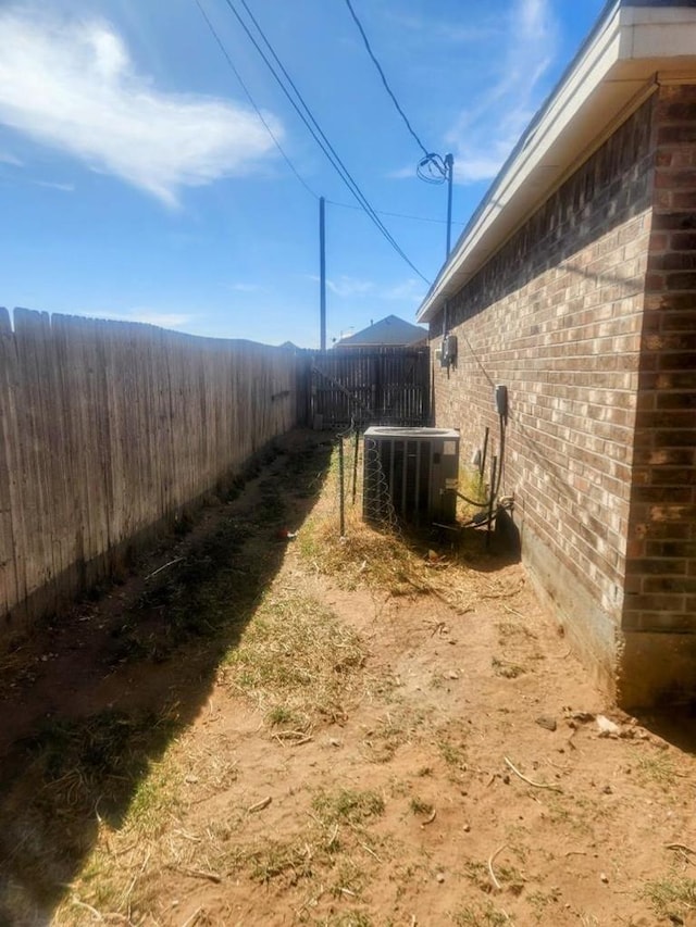 view of home's exterior with central air condition unit, fence, and brick siding