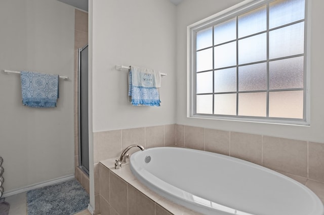 bathroom with a stall shower, a healthy amount of sunlight, and a garden tub