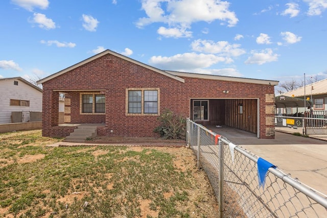 rear view of house with a garage, concrete driveway, brick siding, and fence