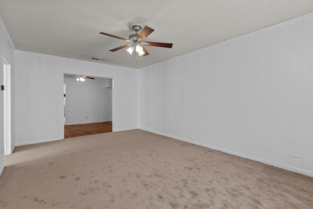 carpeted spare room featuring a textured ceiling, baseboards, visible vents, and a ceiling fan