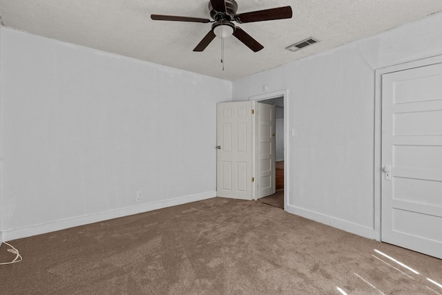 unfurnished bedroom with a textured ceiling, carpet flooring, visible vents, and baseboards