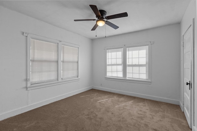 carpeted empty room with a ceiling fan and baseboards