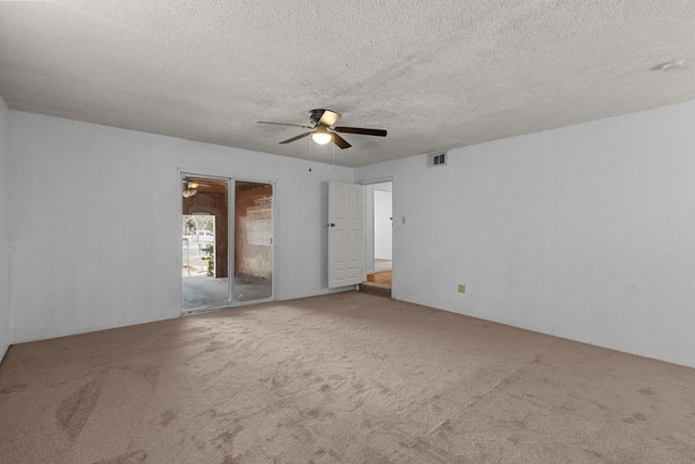 spare room with a textured ceiling, carpet floors, visible vents, and a ceiling fan