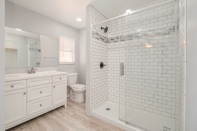 bathroom featuring a stall shower, toilet, vanity, and wood finished floors