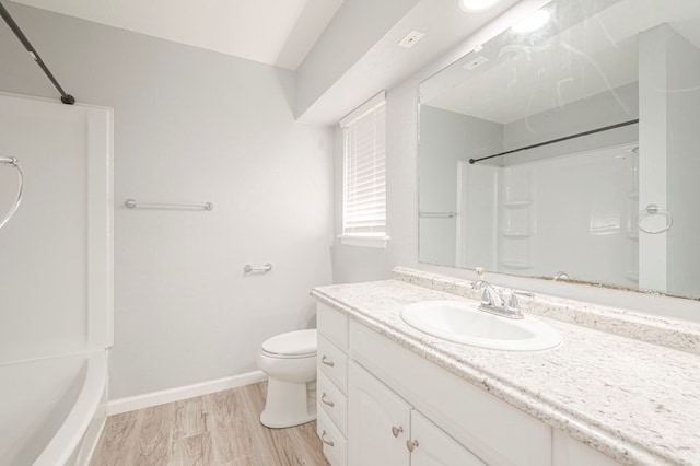 bathroom with toilet, wood finished floors, shower / bathing tub combination, baseboards, and vanity