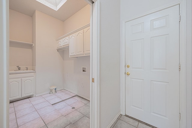 washroom featuring sink, washer hookup, light tile patterned floors, and a skylight