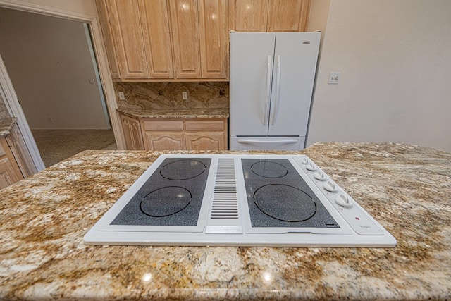 kitchen featuring tasteful backsplash, light stone counters, light brown cabinetry, and white appliances