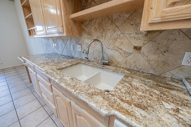 kitchen featuring light brown cabinetry, sink, tasteful backsplash, light tile patterned floors, and light stone countertops