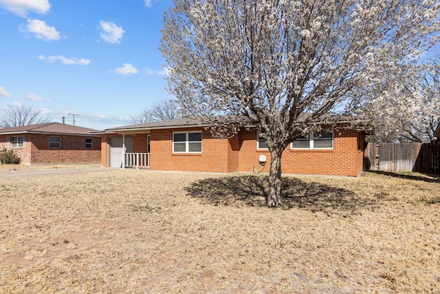 view of front of home featuring brick siding, driveway, an attached garage, and fence