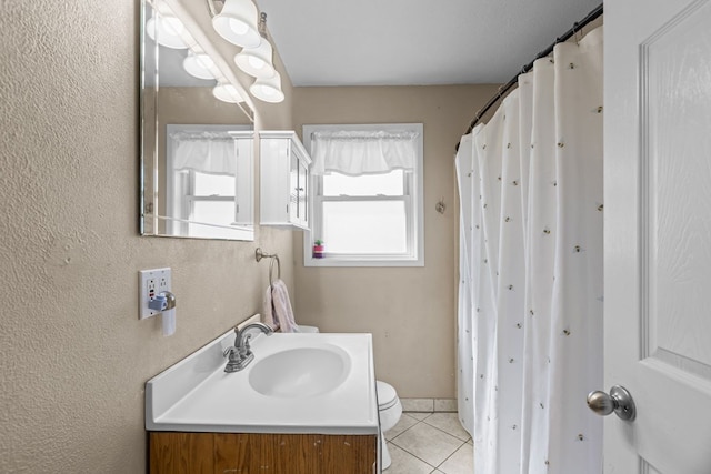 bathroom with toilet, vanity, and tile patterned flooring