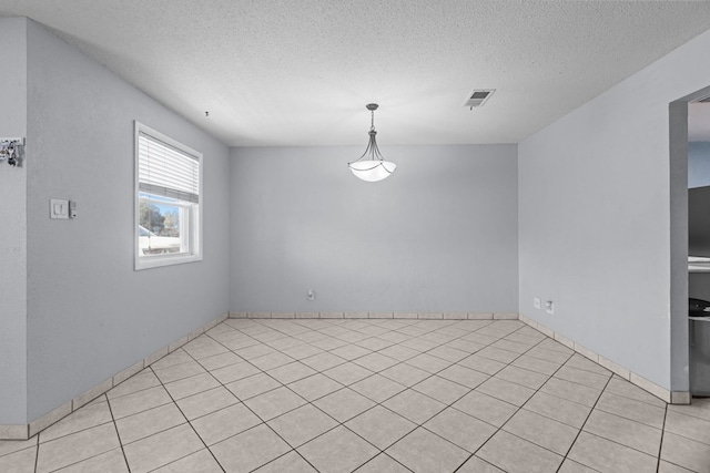 empty room featuring light tile patterned floors, visible vents, and a textured ceiling