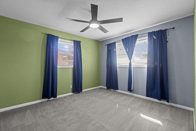 spare room with a textured ceiling, carpet, baseboards, and a healthy amount of sunlight