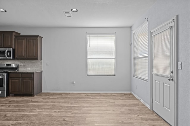 kitchen with stainless steel appliances, visible vents, dark brown cabinetry, light wood-type flooring, and baseboards