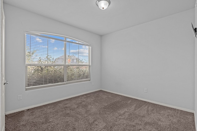 carpeted spare room featuring baseboards