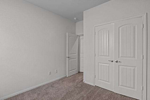 unfurnished bedroom featuring a closet, carpet, and baseboards