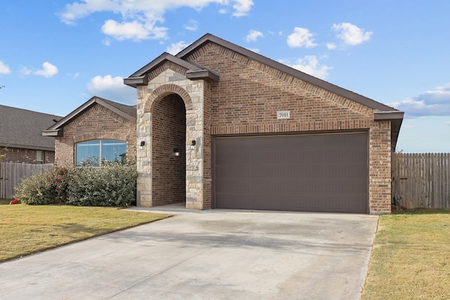 view of front of property featuring concrete driveway, brick siding, an attached garage, and fence