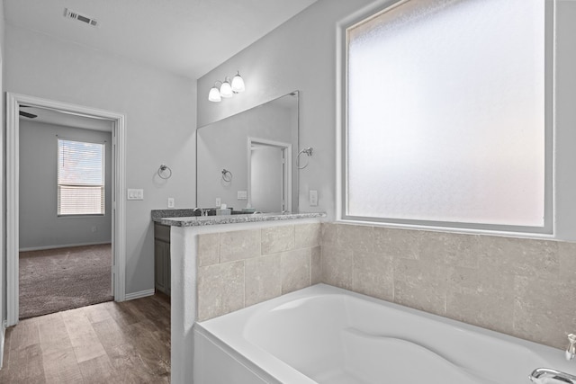 full bathroom with a garden tub, visible vents, wood finished floors, and vanity