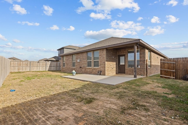 back of house with a patio area, a fenced backyard, a yard, and brick siding