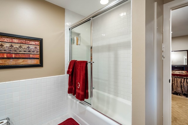 bathroom featuring shower / bath combination with glass door and tile walls