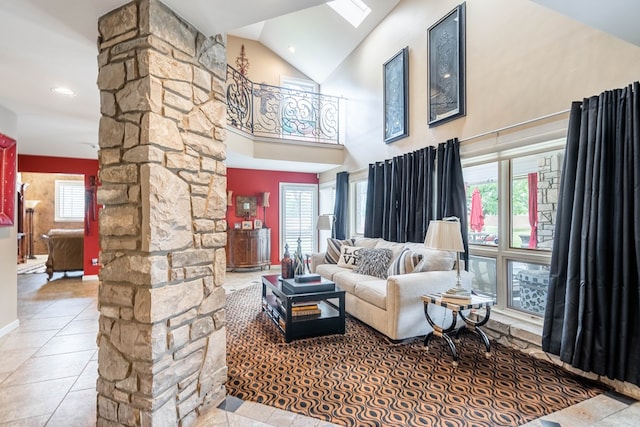 living room featuring a healthy amount of sunlight, light tile patterned flooring, ornate columns, and high vaulted ceiling