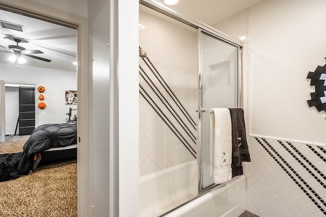 bathroom featuring ceiling fan, enclosed tub / shower combo, and tile walls