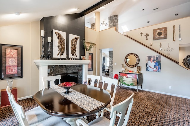 dining area with a premium fireplace, carpet floors, and high vaulted ceiling