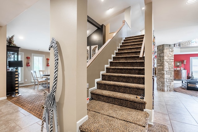 stairs with tile patterned floors, a high ceiling, and a wealth of natural light