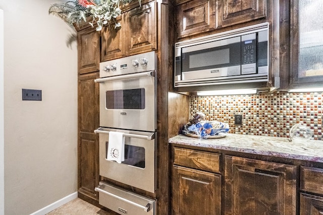 kitchen with decorative backsplash, dark brown cabinetry, light stone countertops, and appliances with stainless steel finishes