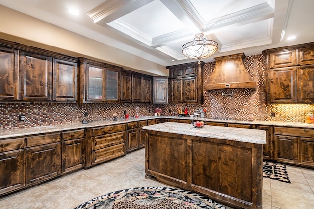 kitchen with premium range hood, tasteful backsplash, a kitchen island, light stone counters, and dark brown cabinetry