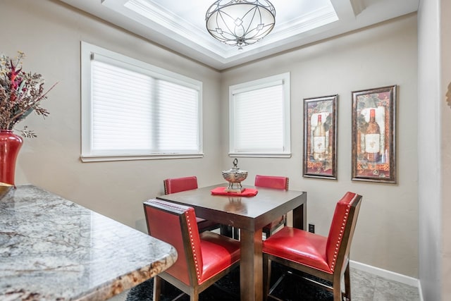 dining space featuring a raised ceiling, ornamental molding, and a notable chandelier