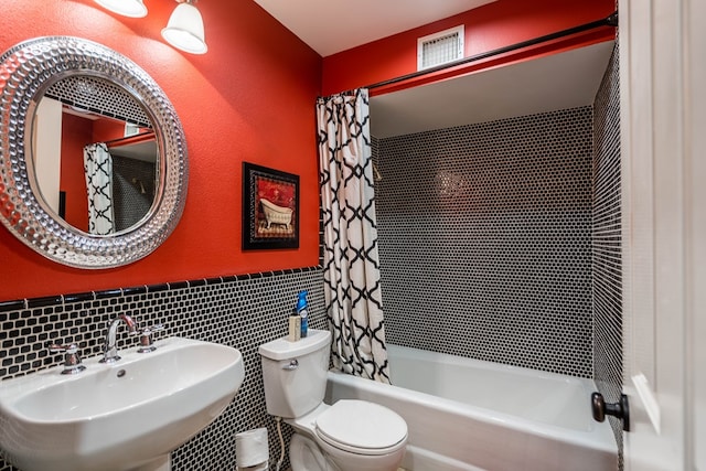 full bathroom with shower / bath combo with shower curtain, sink, tile walls, and toilet