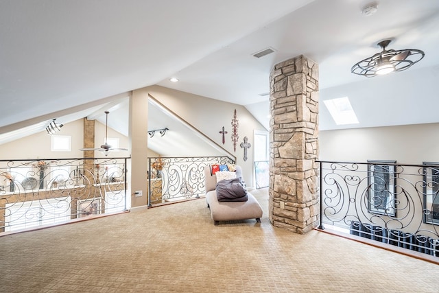 living area featuring decorative columns, ceiling fan, carpet floors, and lofted ceiling with skylight