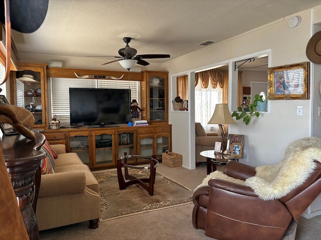 carpeted living room featuring visible vents, a textured ceiling, and ceiling fan