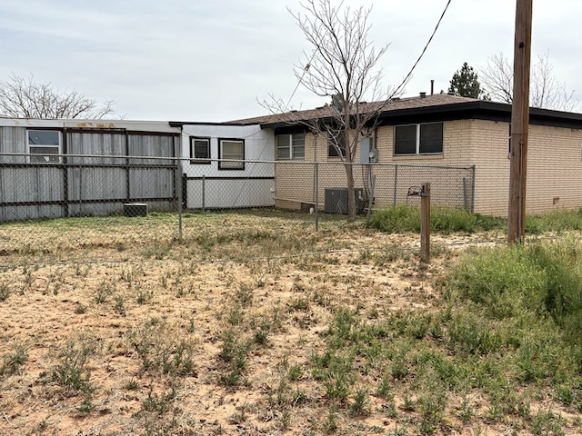 rear view of house featuring brick siding and fence