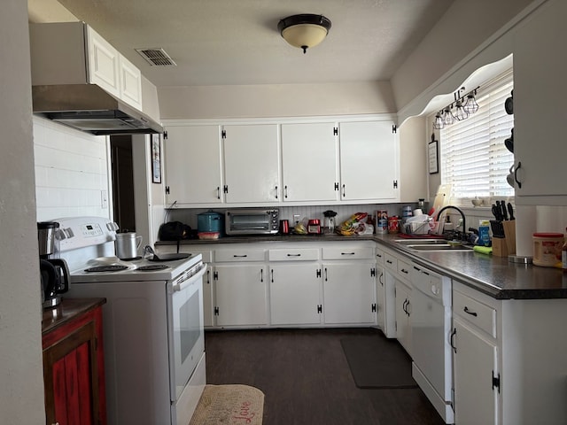 kitchen featuring visible vents, a sink, dark countertops, white appliances, and wall chimney exhaust hood