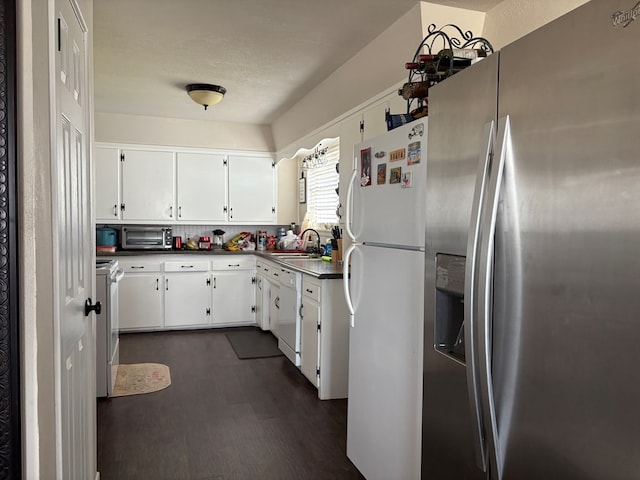 kitchen with a sink, dark countertops, white cabinetry, white appliances, and dark wood-style flooring