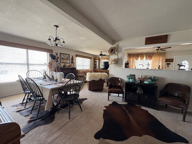 carpeted dining room featuring a textured ceiling and ceiling fan with notable chandelier