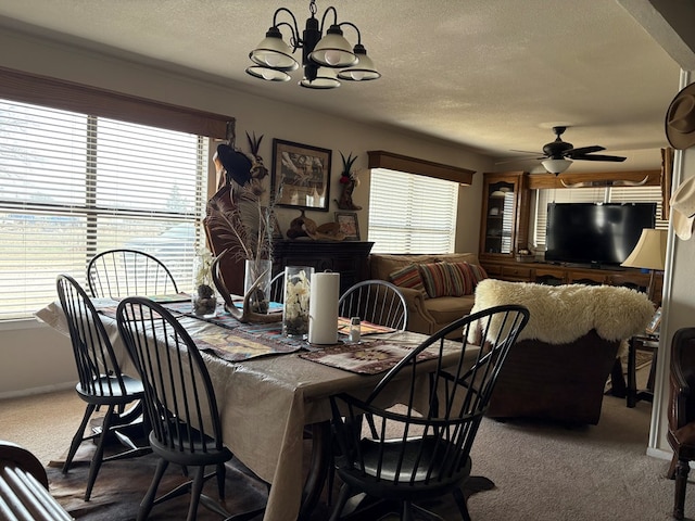 carpeted dining area with plenty of natural light, a textured ceiling, and ceiling fan with notable chandelier