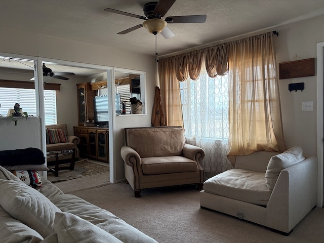 carpeted living area with a textured ceiling, a healthy amount of sunlight, and ceiling fan