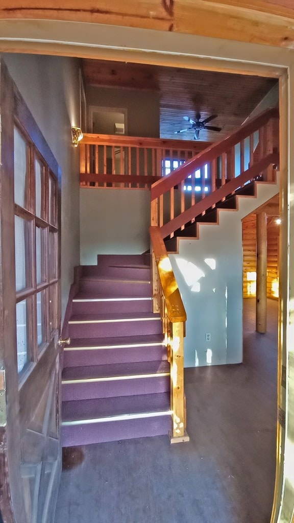 stairway with ceiling fan and concrete floors