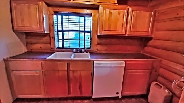 kitchen featuring white dishwasher, rustic walls, and sink