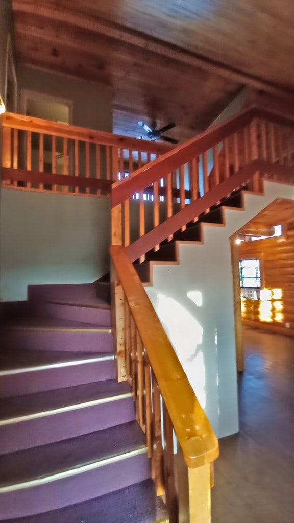 stairway featuring concrete floors, ceiling fan, and wooden ceiling