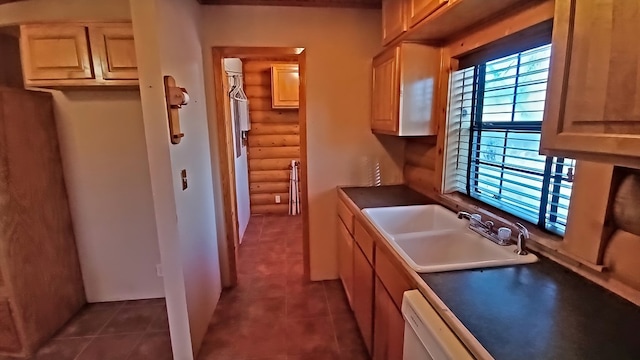 kitchen with dishwasher, light brown cabinets, dark tile patterned floors, and sink