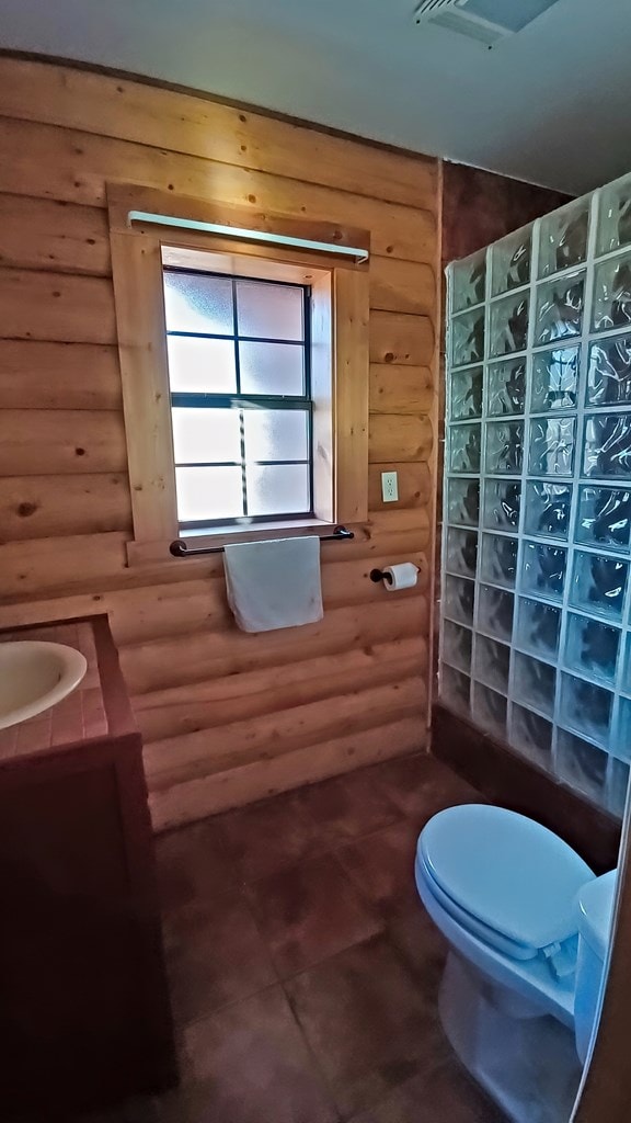 bathroom featuring toilet and rustic walls