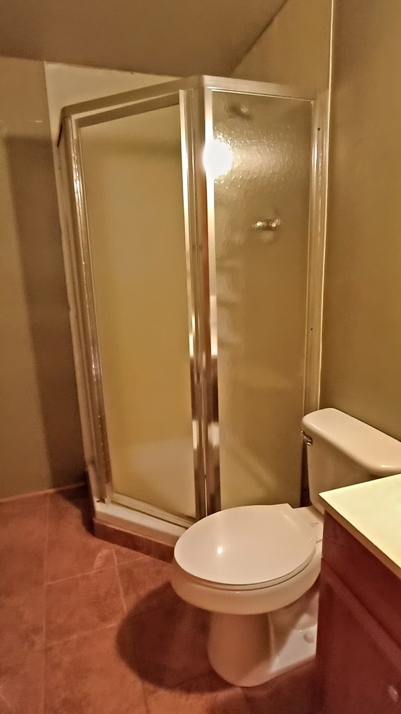 bathroom with toilet, vanity, tile patterned floors, and a shower with door